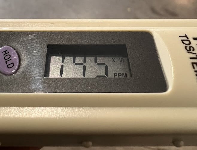 TDS meter display showing a reading with a small x10 symbol after the number